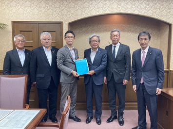 財務省藤原財務大臣政務官へ手交（写真左から3人目）